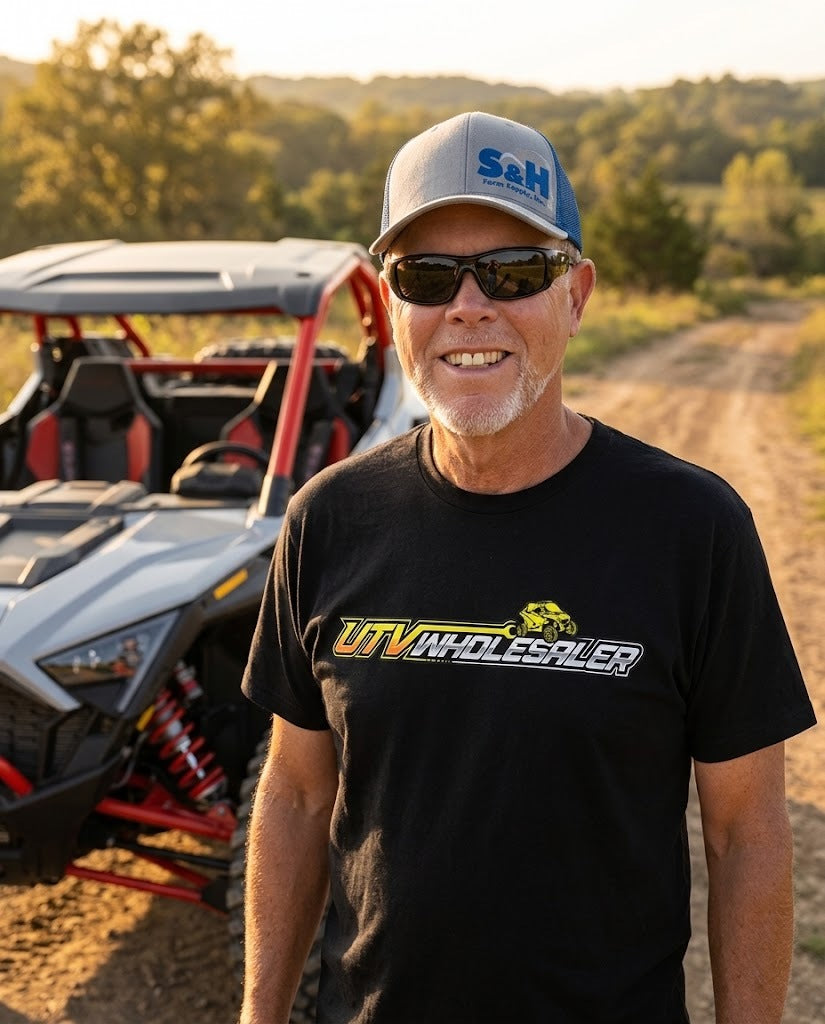 Marshall in a UTV Wholesaler shirt next to a side-by-side on a dirt trail